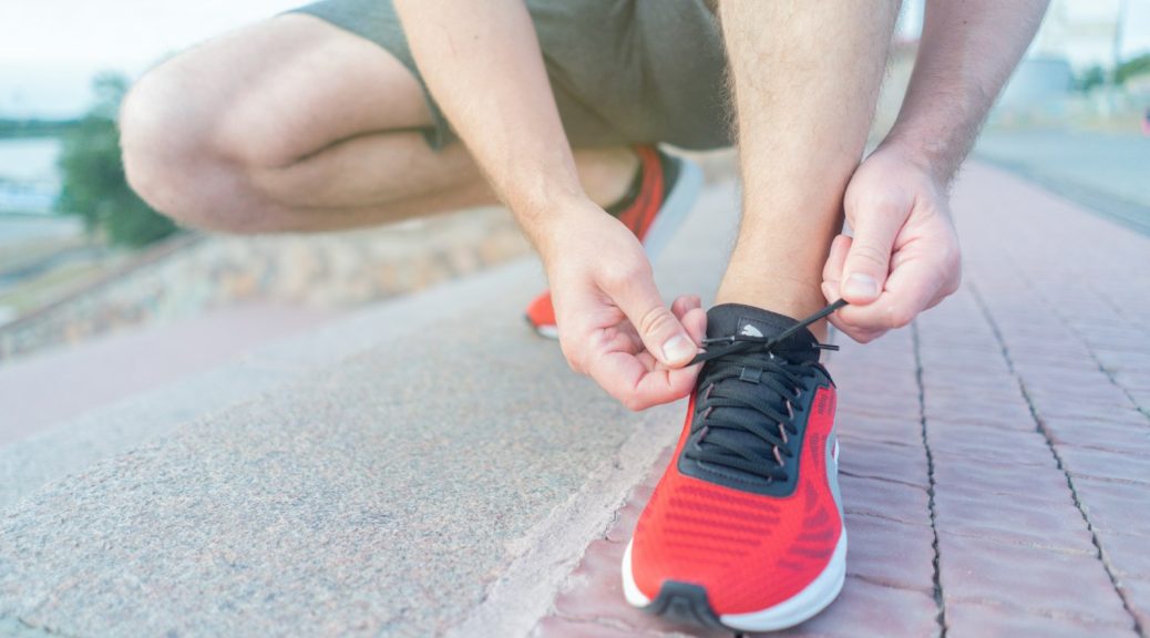 A person tying the laces of red running shoes