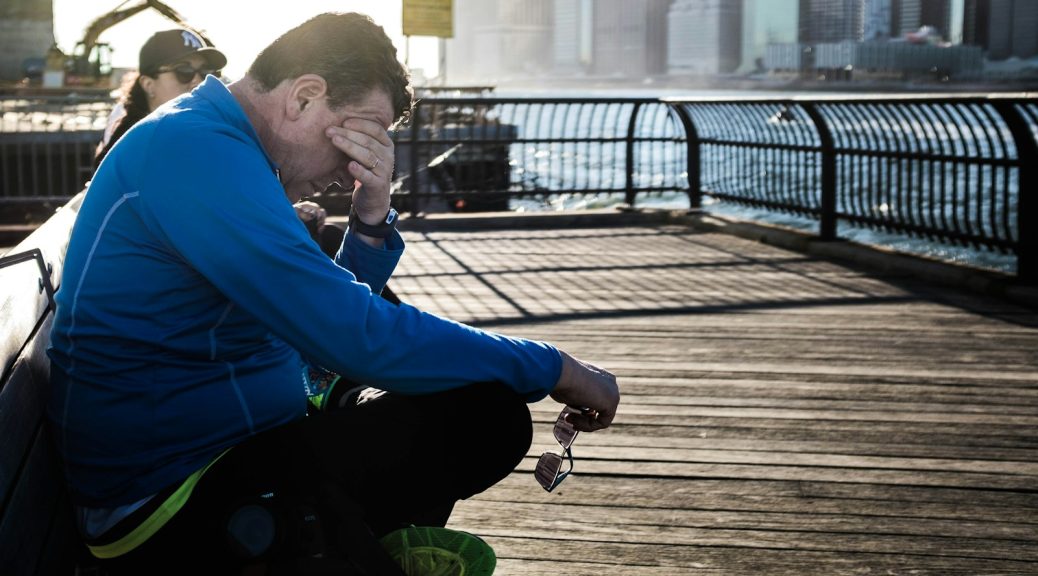 A runner resting on a bench by the water after a workout