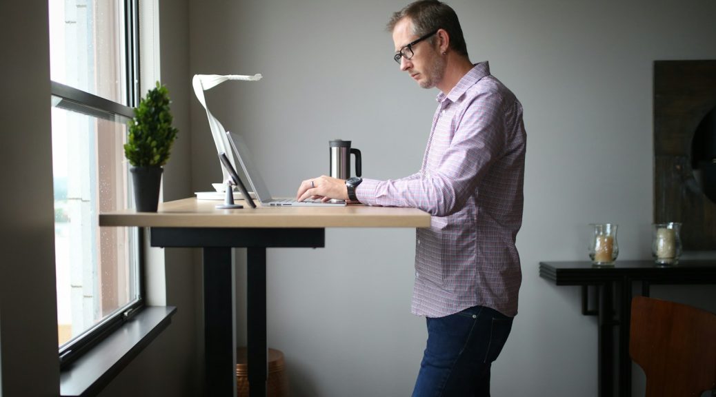A man working at a standing desk beside a window