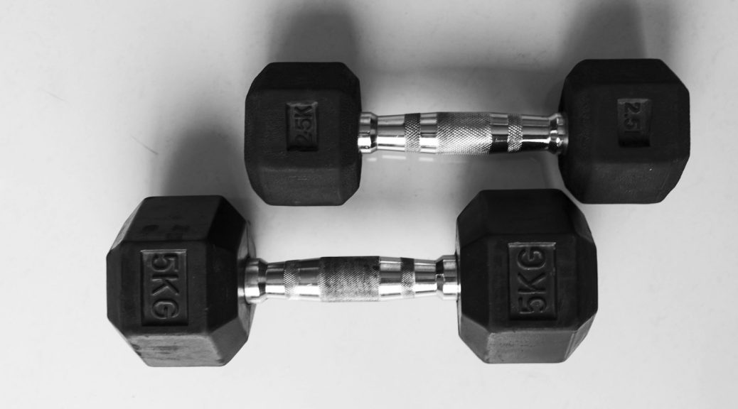 A pair of black hexagonal dumbbells on a white surface