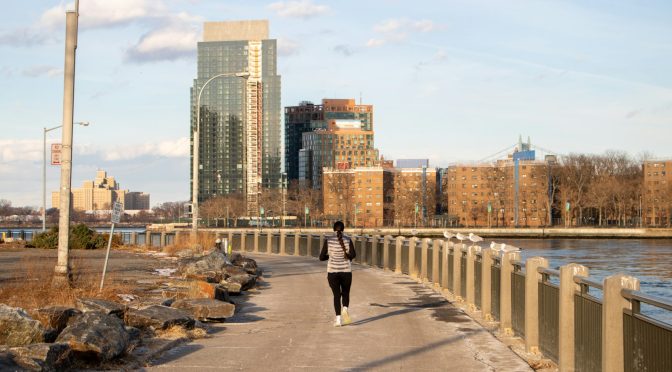 A woman jogging along a waterfront path in the city
